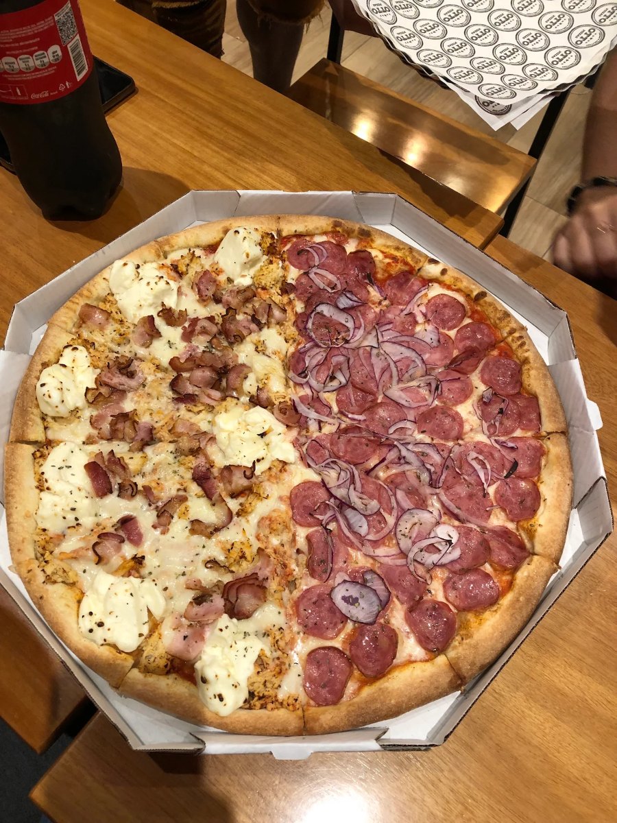 Pizza meio a meio da Otto na caixa octogonal, servida no salão