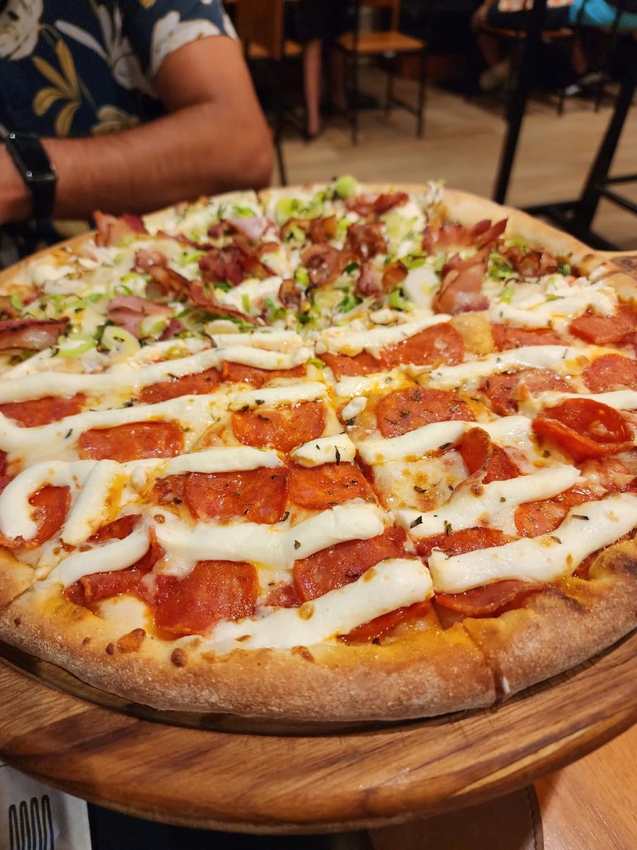 Pizza meio a meio da Otto servida na tábua de madeira