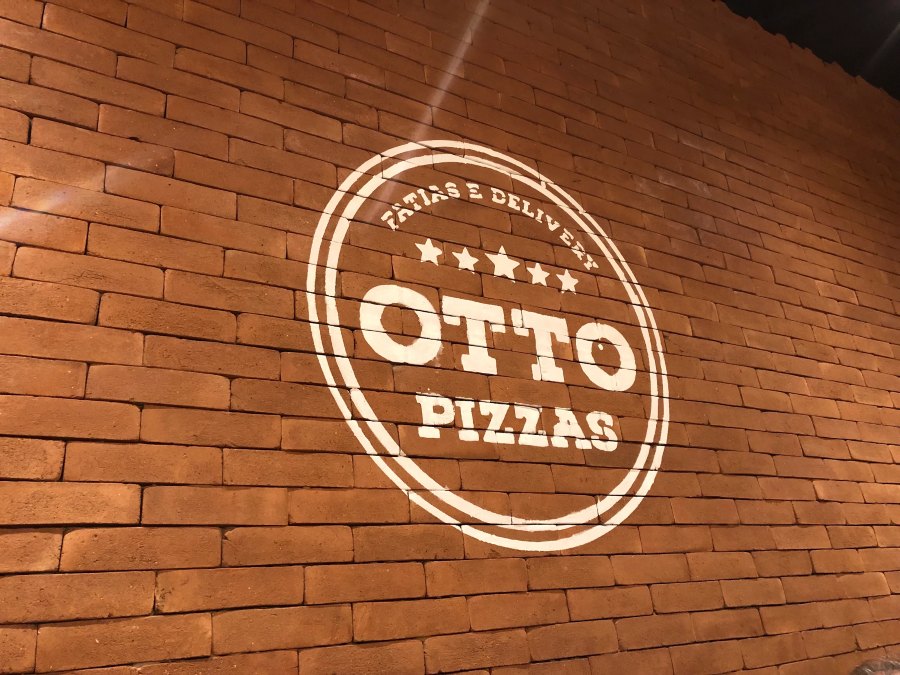 Logo da Otto Pizzas pintado na parede de tijolos da loja