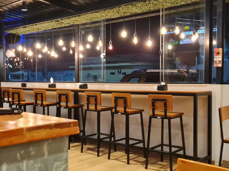 Salão da Otto Pizzas à noite, com bancada e luminárias